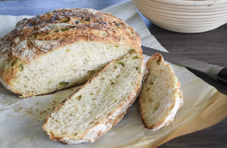 Sliced Jalapeño cheddar sourdough boule on parchment paper