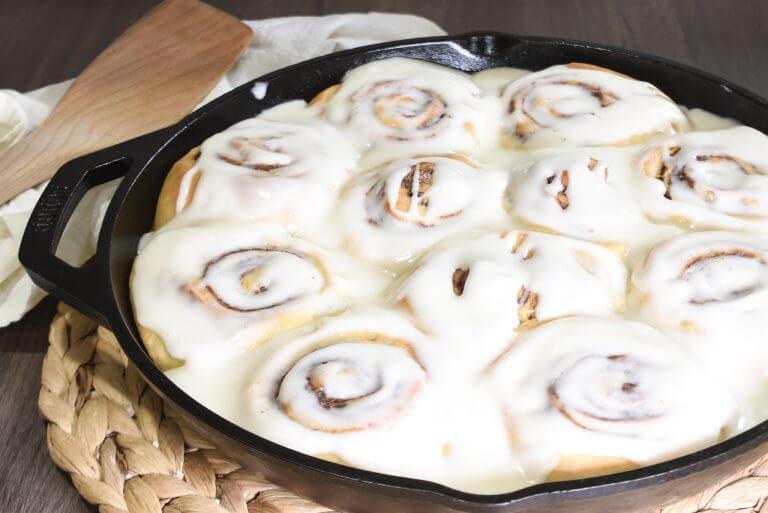 Glazed sourdough cinnamon rolls in a cast iron skillet