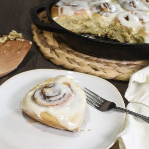 Sourdough cinnamon roll on a plate with fork and spatula on table