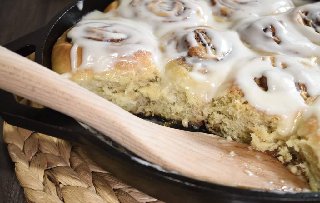Sourdough cinnamon rolls in a cast iron skillet with a spatula