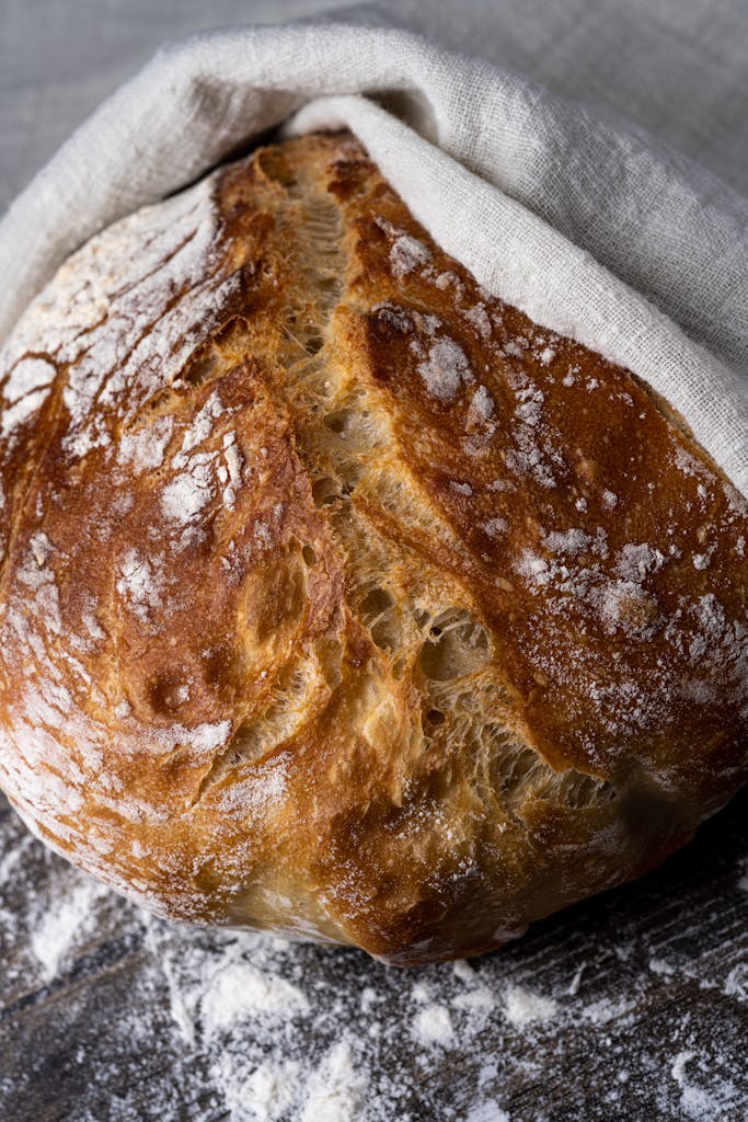 Close-up of a freshly baked artisan sourdough bread resting on a floured surface.