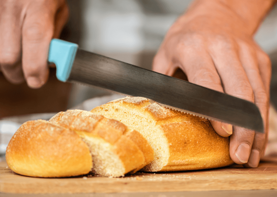 A person cutting bread on a cutting board using a best sourdough bread knife