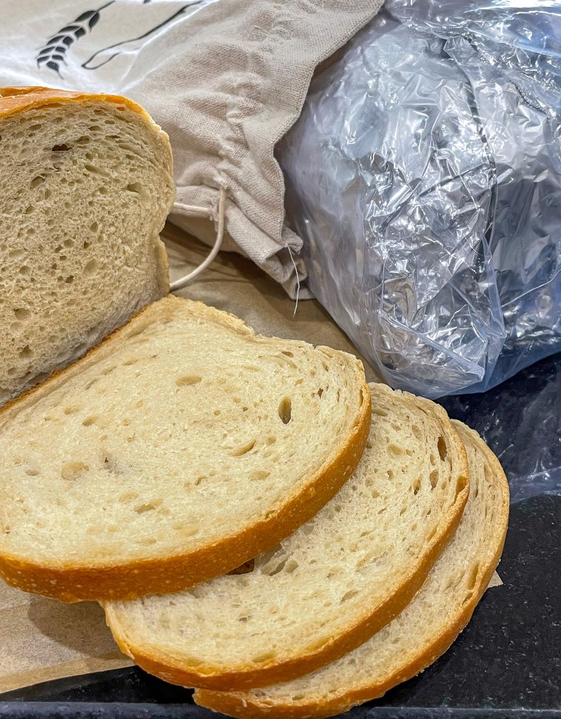 Sliced sourdough bread with another loaf wrapped in aluminum foil to show how to freeze sourdough bread or how long does sourdough bread last