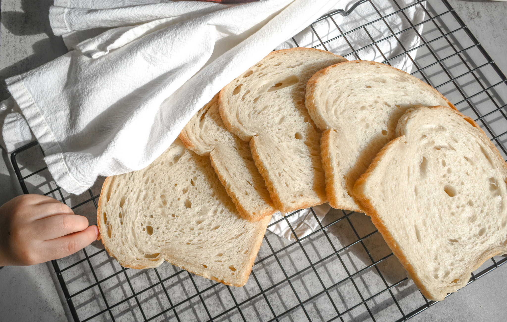 Soft sourdough sandwich bread on a cooling rack